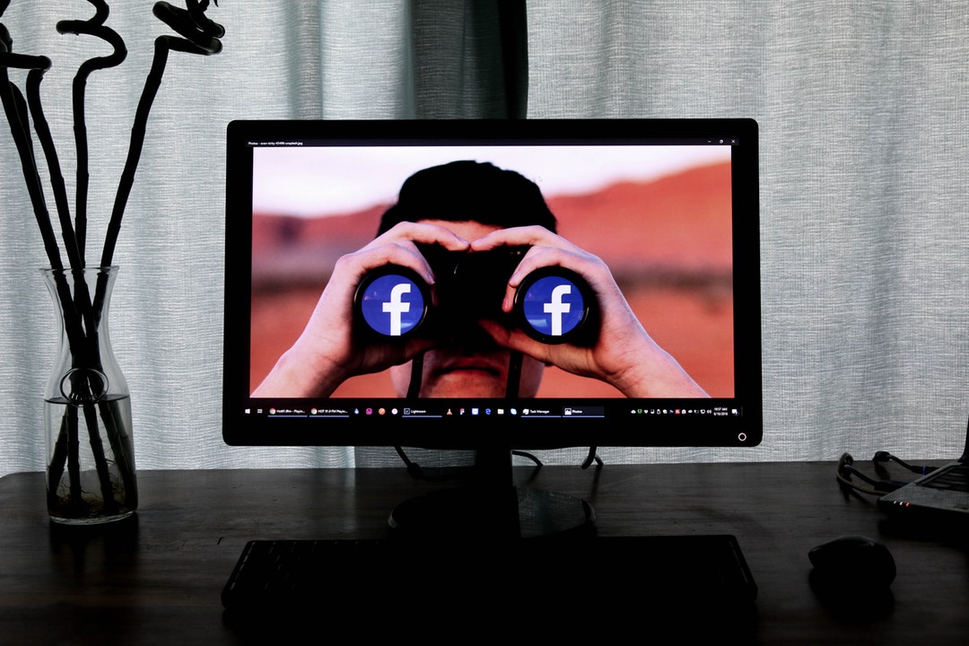 facebook logo on binoculars on computer screen