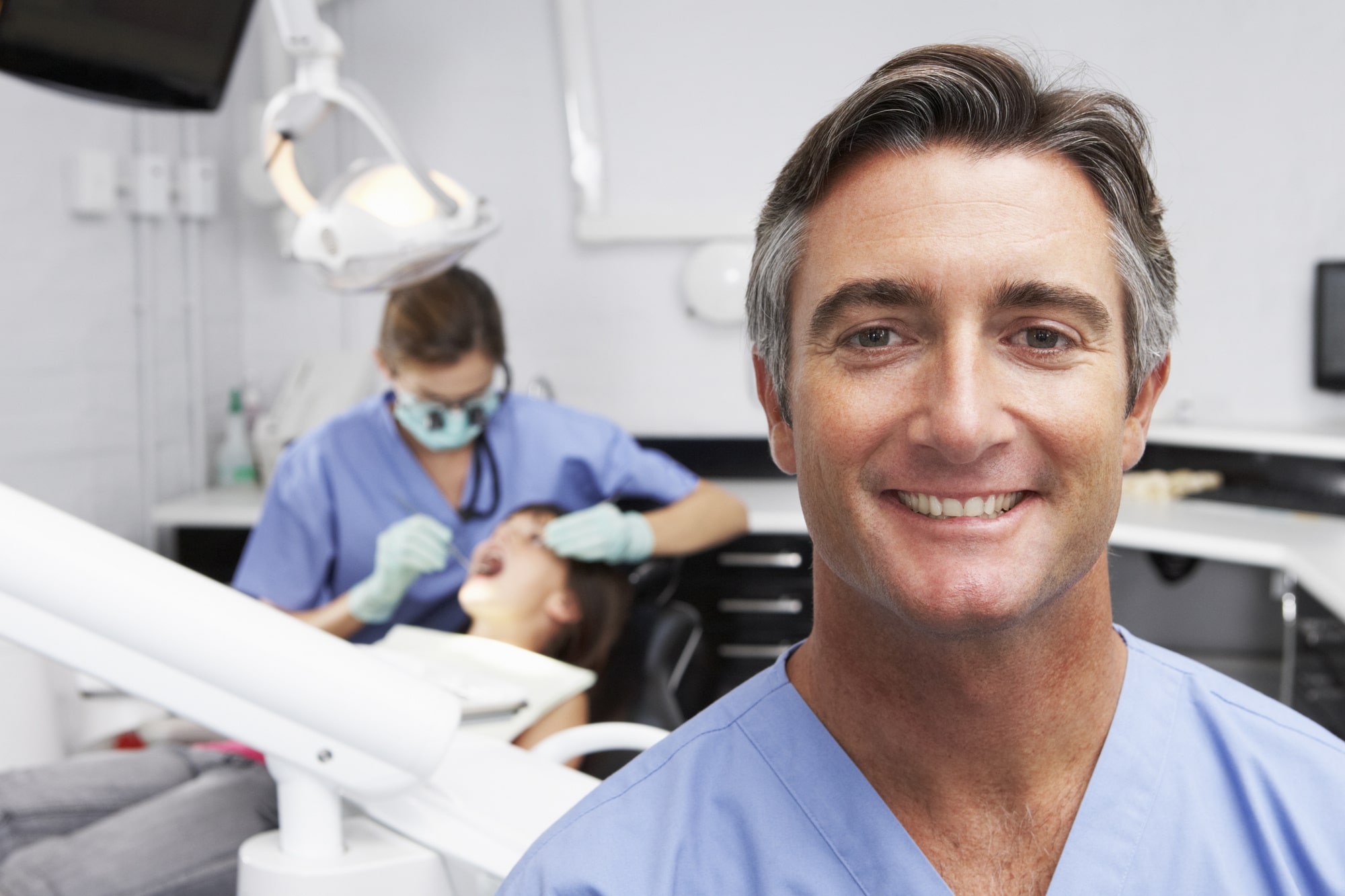 dentist with patient and technician in background